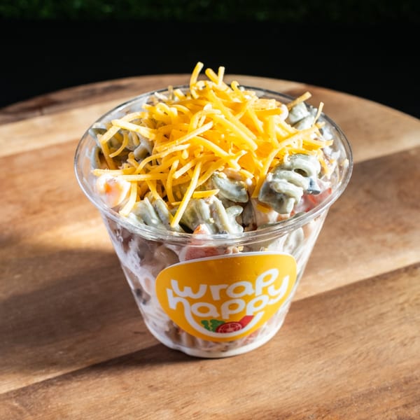 Wrap Happy salad cup filled with pasta, vegetables, creamy dressing, and shredded cheese.