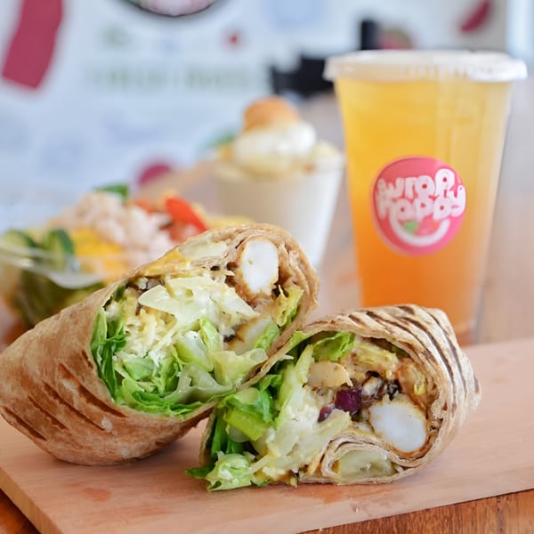 A grilled Wrap Happy wrap, cut in half, filled with shrimp, lettuce, and cheese, with a drink.