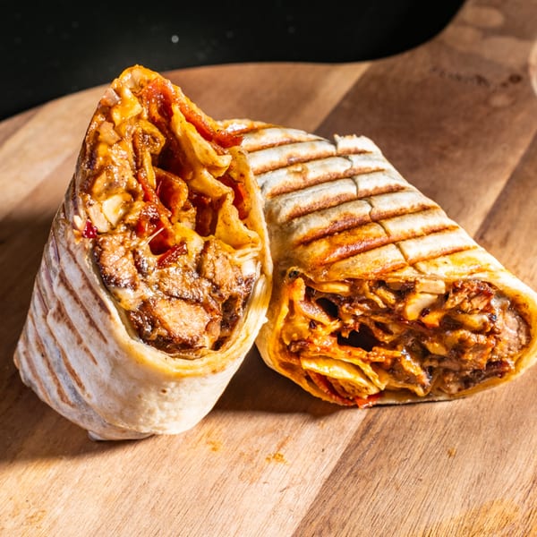 Two grilled Wrap Happy wraps, cut in half, revealing savory fillings on a wooden board.
